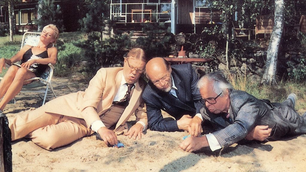 Koomikot lesittävät lapsia, taustallla Hannele Lauri.