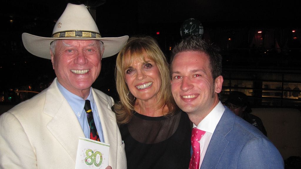 Larry Hagman ja Linda Gray poseeraavat Kimin kanssa.