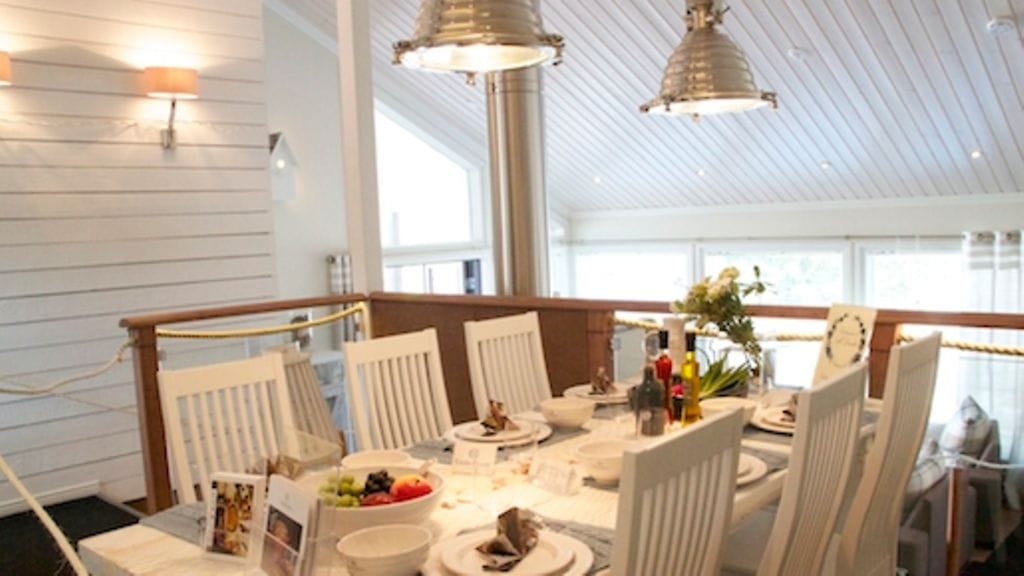 Valkoiseksi maalatut paneelit saavat pienenkin tilan näyttämään väljemmältä. Valkoinen ruokapöytä on katettu kauniin elegantisti.