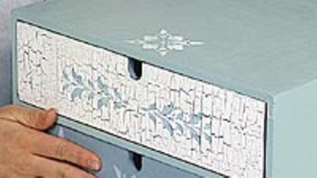 Krakleeraamalla ja oljyväripuikoilla koristeltu lipasto