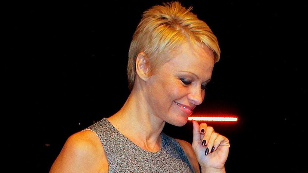 Pamela Andersonin harmaassa mekossa on kaunis, epäsymmetrinen helma.