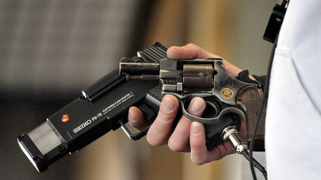 Syytetty ampui velan perijää muunnellulla starttipistoolilla käteen. Kuvituskuva.