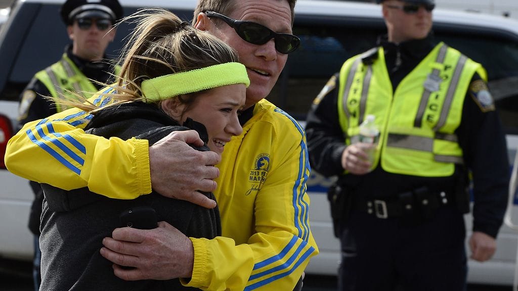 Järkyttyneet ihmiset tukeutuivat toisiinsa Bostonin maratonin maalisuoralla tapahtuneiden räjähdysten jälkeen.