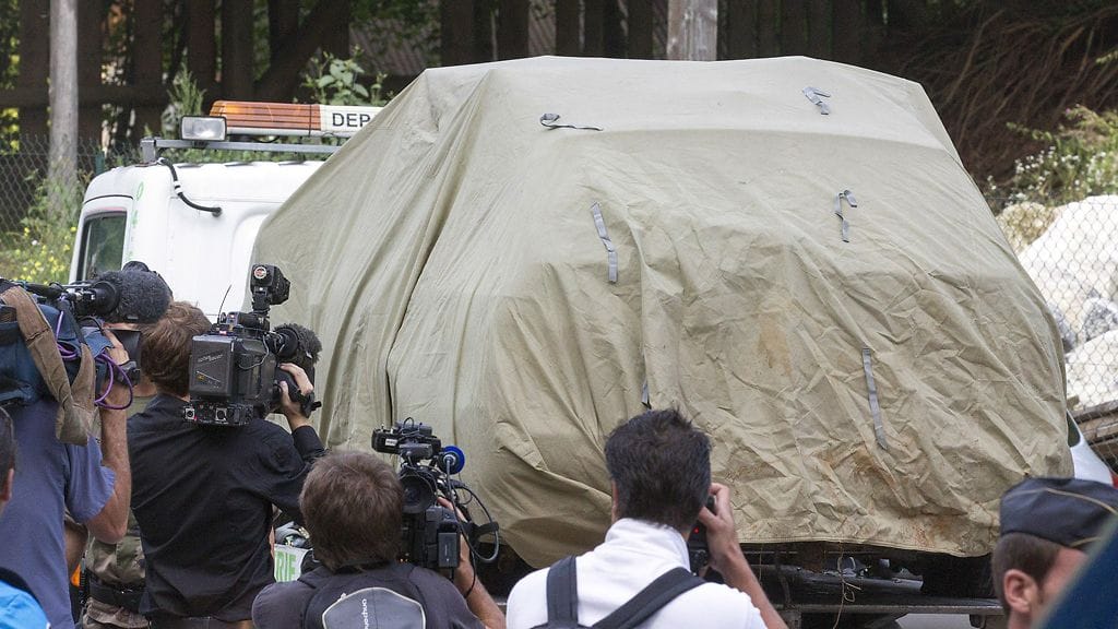 Alpeilla joukkosurman uhreiksi joutuneiden autoa kuljetetaan pois.