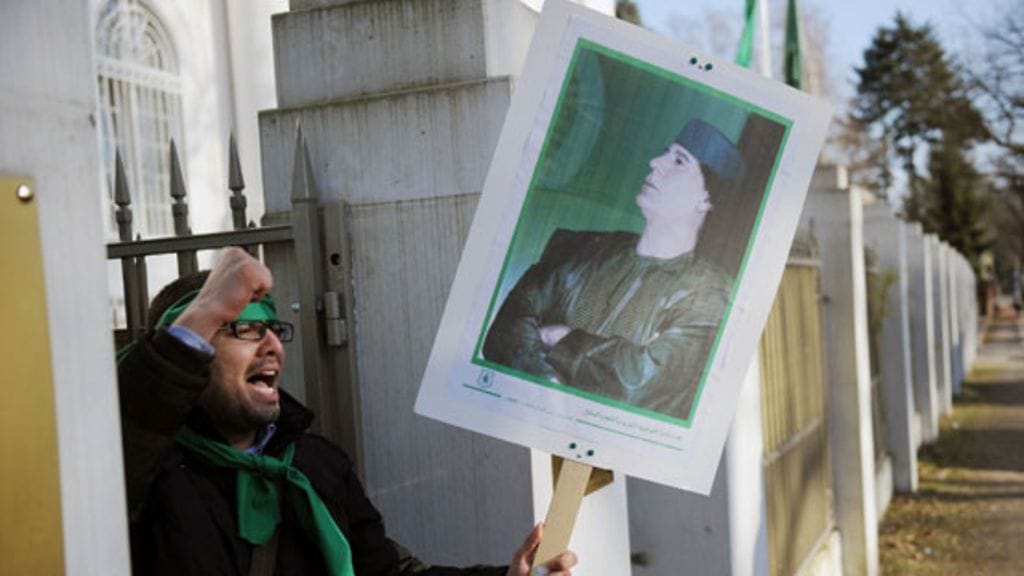 Libyan johtajan Muammar Gaddafin kannattaja kyltteineen.