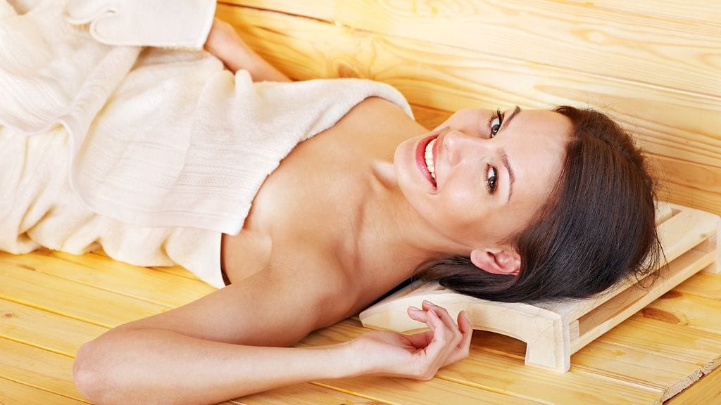 Suomalaisnainen hemmottelee itseään kotona kasvohoidoin, kuorimalla ihoaan ja saunomalla.