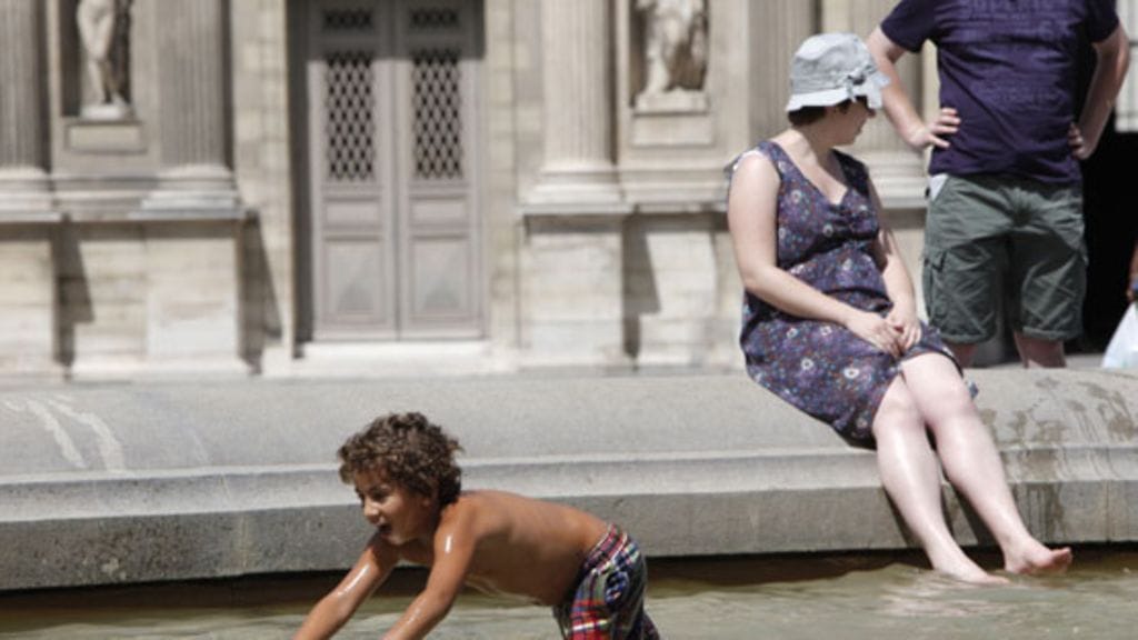 Turistit viilensivät itseään Louvren taidemuseon suihkulähteessä Pariisissa 9.7.2010. Lämpötila on noussut Ranskan pääkaupungissa yli 30 asteeseen.