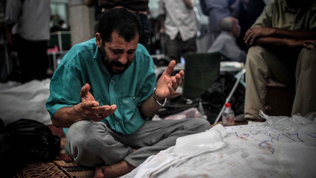 Egyptiläinen mies suree sukulaisensa kuolemaa lukuisten ruumiiden keskellä Kairossa.