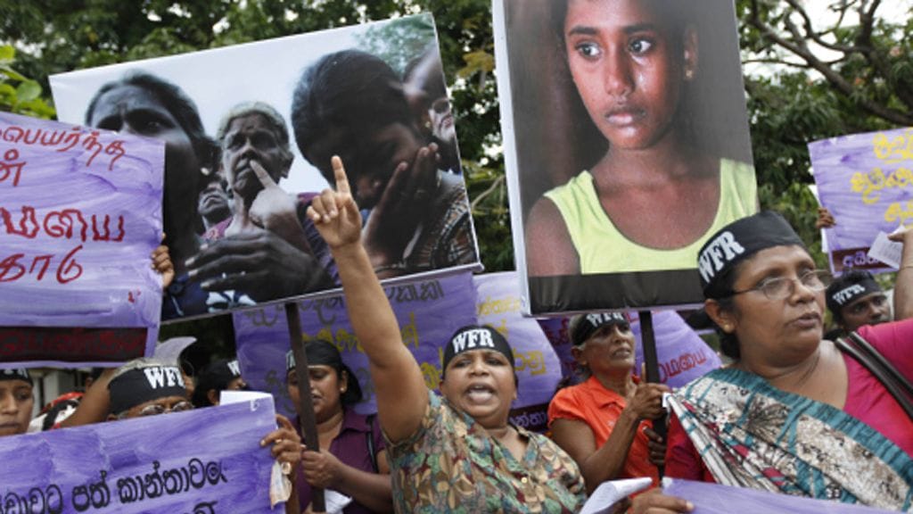 A socialist woman activist shouts slogans during a protest against the rising cost of living and violence against women in Colombo, Sri Lanka, Thursday, March 8, 2012, marking International Women's day. A wave of protests erupted across the island nation during the last weeks after the government increased fuel prices, citing rising world oil prices. Placard on left bottom reads "pay social insurance for women affected by war." (AP Photo/Gemunu Amarasinghe