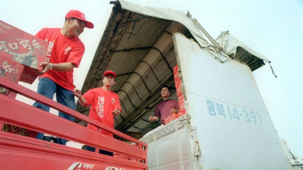Työntekijät lastaavat Coca-Colaa Pohjois-Koreaan meneviin kuorma-autoihin Kiinan ja Pohjois-Korean rajakaupungissa. Kuva: Lehtikuva