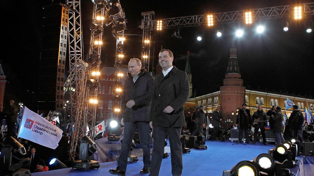 Istuva presidentti Dimitri Medvedev (oik.) ja Venäjän presidentinvaalit tänään voittanut pääministeri Vladimir Putin voitonjuhlassa Moskovan keskustassa.
