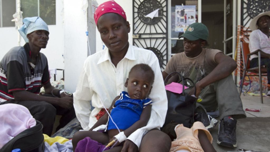 Äiti jonottaa lapsensa kanssa pääsyä sairaalaan Haitissa vuonna 2010.