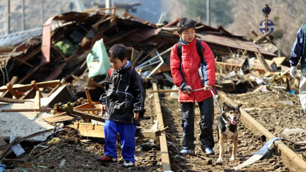 Japanilaislapset katselevat maanjäristyksen ja tsunamin aiheuttamia tuhoja Kamaishin kaupungissa 13.3.2011. Yli 80 lasta on jäänyt orvoksi luonnonkatastrofin jäljiltä.