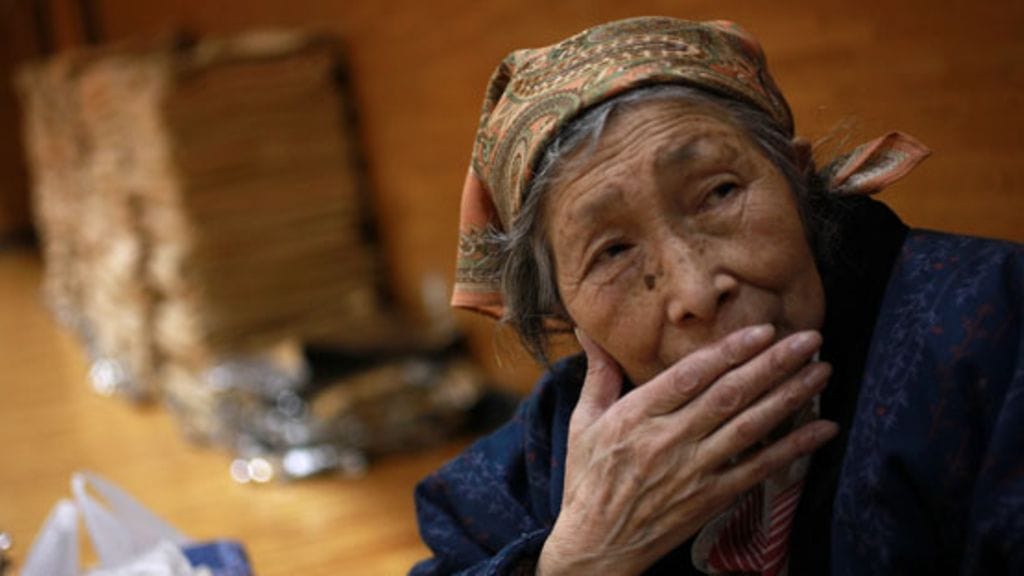 80-vuotias nainen lepää evakuointikeskuksessa Aomorin maakunnassa. Vanhukset kärsivät kylmästä sekä ruuan ja juoman puutteesta. Kuva: EPA