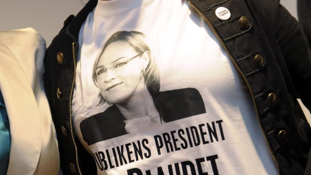 Vähemmistövaltuutettu Eva Biaudetin presidentinvaalikampanjan T-paita ministeri Rehnin ja RKP:n yhteisessä lehdistötapahtumassa Helsingissä 30. elokuuta 2011 (Kuva: Lehtikuva).