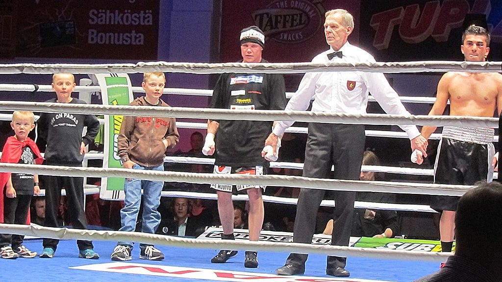Juho Tolppola (tuomarista vasemmalla) kehässä poikiensa kanssa ottelun jälkeen.