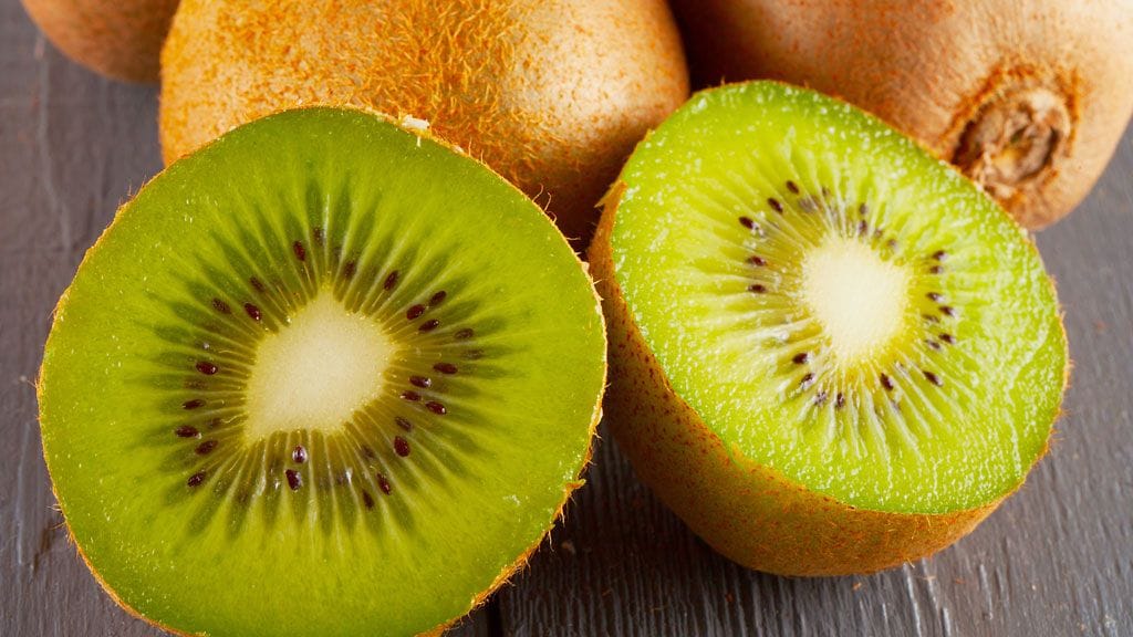Moni leikkaa kiivin kahtia päästäkseen käsiksi hedelmälihaan – ja heittää sen jälkeen kuoret roskiin.