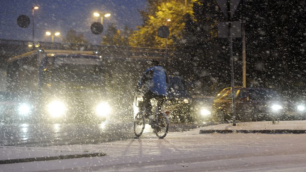Pyöräilijä ylittää suojatietä ensilumen sataessa Helsinkiin 26. lokakuuta 2012.