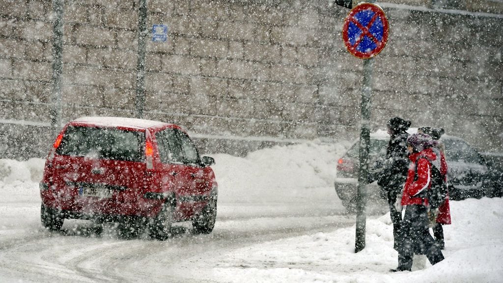 Auto ja ihmisiä lumisateessa Unioninkadulla Helsingissä 20. tammikuuta 2012.