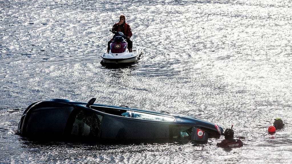 Parkkipaikalta Kemijokeen liukunutta autoa hinataan maihin Rovaniemen Ounaskosken uimarannan lähellä 16. heinäkuuta 2014. Auto osui liukuessaan aurinkoa ottaneeseen mieheen, joka kuoli saamiinsa vammoihin.