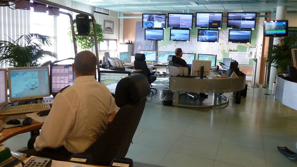 Taustalla viestioperaattori Suomenlahden merivartioston johtokeskuksessa tarkkailee tutka- ja kamerakuvia.