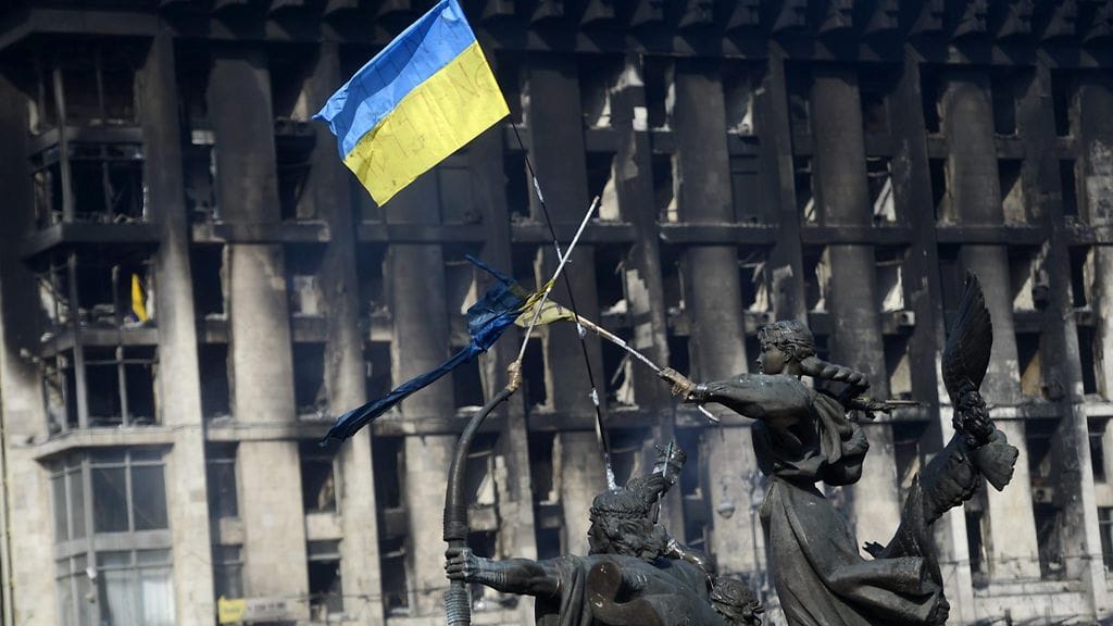 Ukrainan lippu liehuu palaneen rakennuksen edustalla Kiovassa helmikuussa 2014. Kuvituskuva.