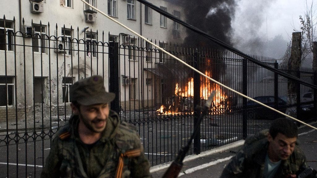Kapinallistaistelijat pakenivat palavan auton luota Ukrainan armeijan pommitusten jälkeen Donetskissa 26.8.2014.