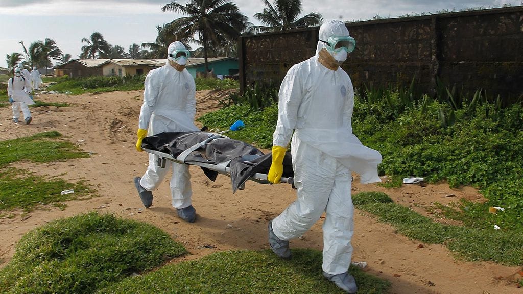 Terveystyöntekijät kantavat Ebola-uhrin ruumista Liberiassa.