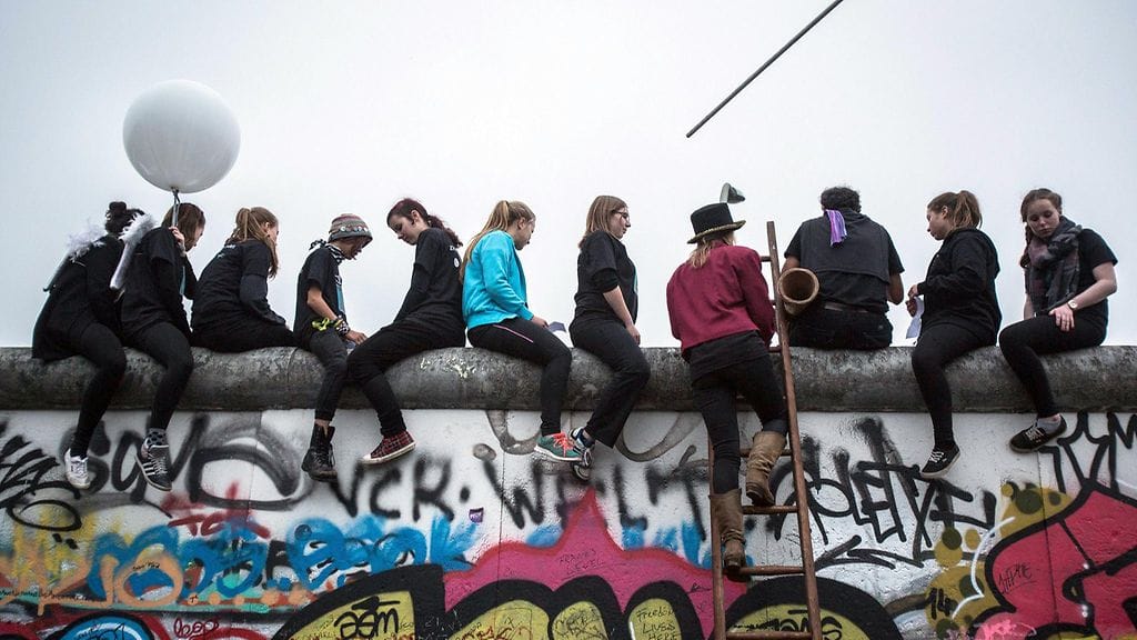 Nuoret istuivat East Side Gallery-nimellä tunnetun muurinpätkän päällä Berliinissä 9. lokakuuta 2014.