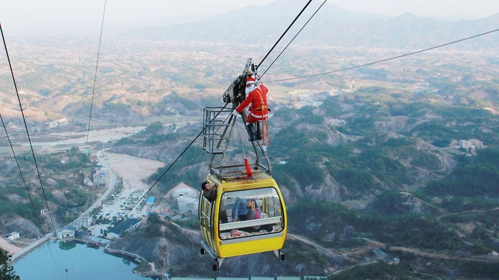 Joulupukiksi pukeutunut henkilökunnan jäsen jakaa hlahjoja turisteille hurjassa paikassa Pingjangissa, Kiinassa.