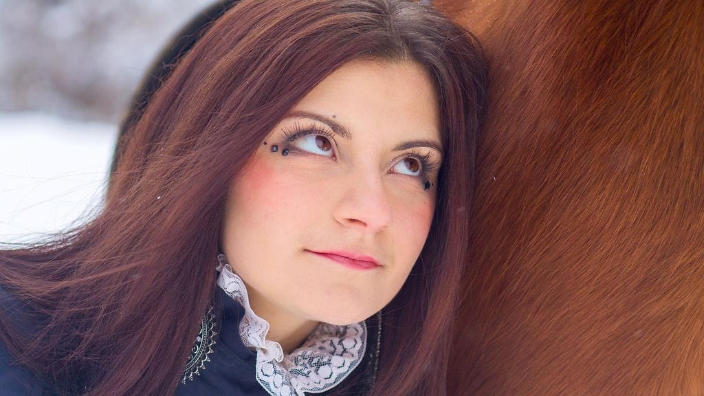 Nainen talvisessa metsässä hevosen kanssa