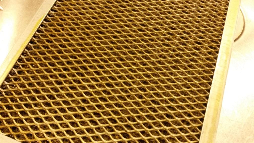 Rasvainen liesituulettimen suodatin. Lika näkyy rusehtavana pinnalla.