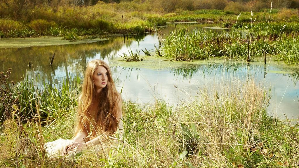 Nainen metsässä lammen rannalla