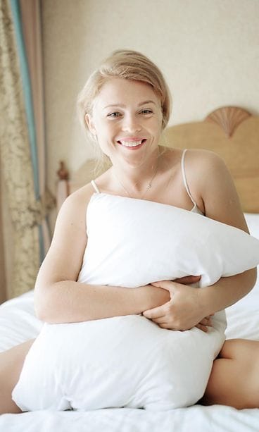 Nainen hymyilee sängyssä