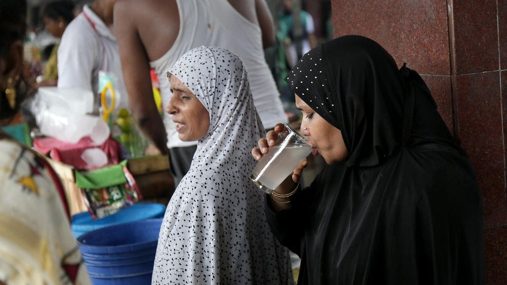 Intialaisnainen juo sitruunavettä kovassa kuumuudessa maan itärannikolla Kalkutassa.