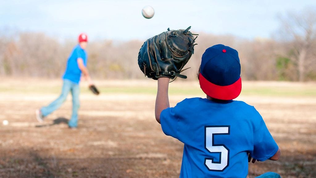Poika pelaa pesäpalloa