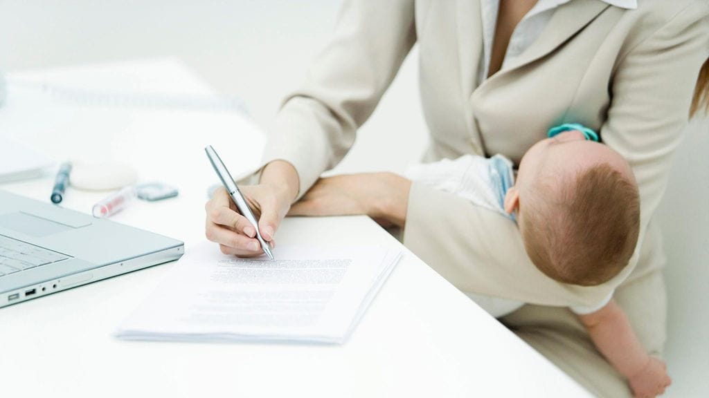 Nainen tekee töitä vauva sylissään