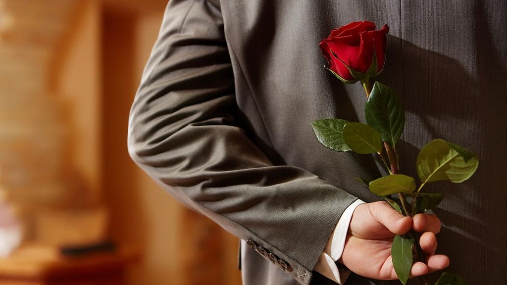 Mies ruusu selän takana