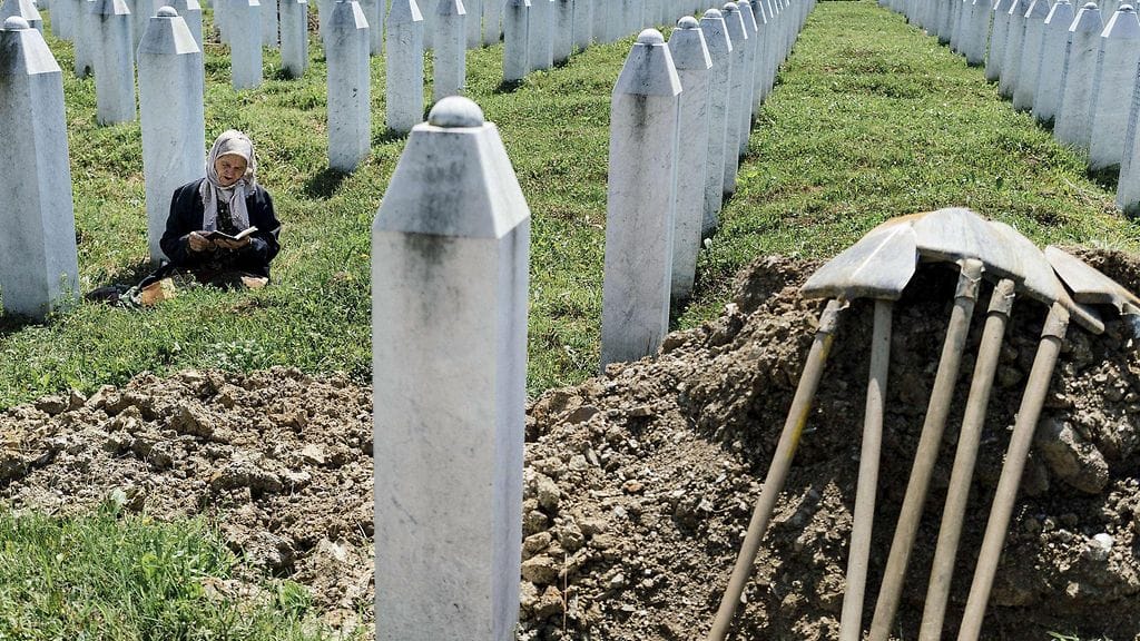 Bosnialainen nainen rukoilee sukulaisensa haudalla Srebrenican verilöylyn -muistokeskuksessa.