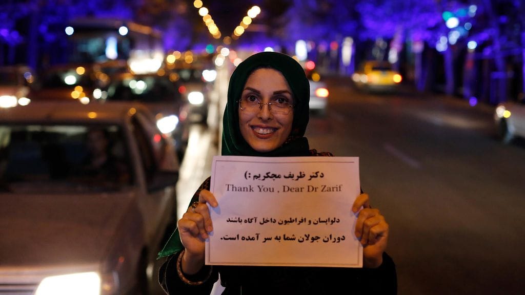 Iranilainen nainen piti ulkoministeri Mohammad Zarifia kiittävää plakaattia käsissään 14. heinäkuuta 2015, kun neuvottelut IAEA:n kanssa onnistuivat. Neuvottelujen tuloksena Iranin luvattiin vapautuvan lähitulevaisuudessa talouspakotteista. Nyt vapautuminen on toteutumassa käytännössä. (EPA)