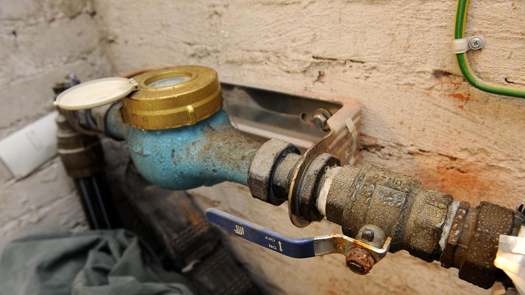 Taloyhtiön päävesijohtomittari ja vesisuljin talon kellarissa.