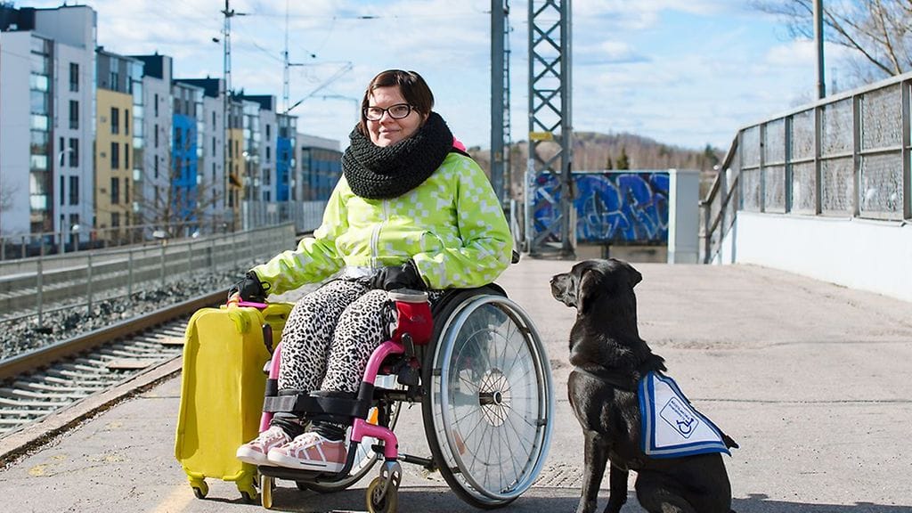 Avustajakoiran käyttäjä matkalla koiran kanssa.