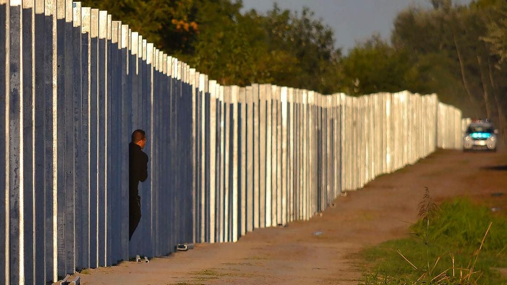Turvapaikanhakija tulossa valmistumassa olevan aidan raosta Unkarin puolelle 7. syyskuuta 2015.