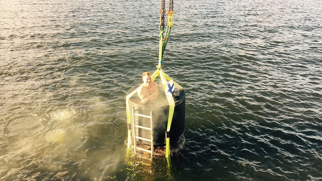 Ari Lehtinen laskeutuu vedenalaiseen saunaan nosturin avulla.