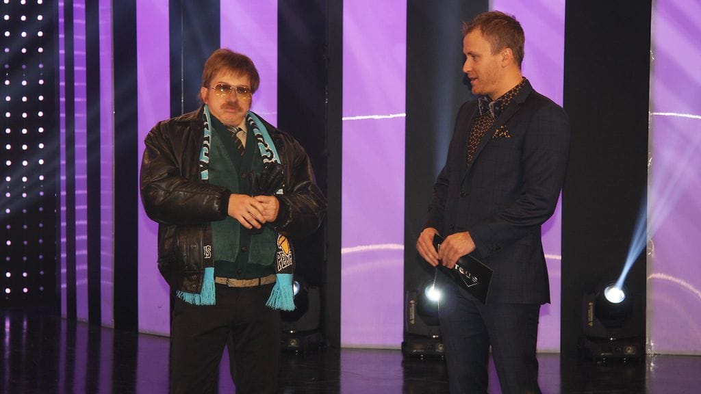 Kari Ketosen sketsihahmo Aimo Sonni juttelemassa juontaja Heikki Paasosen kanssa.