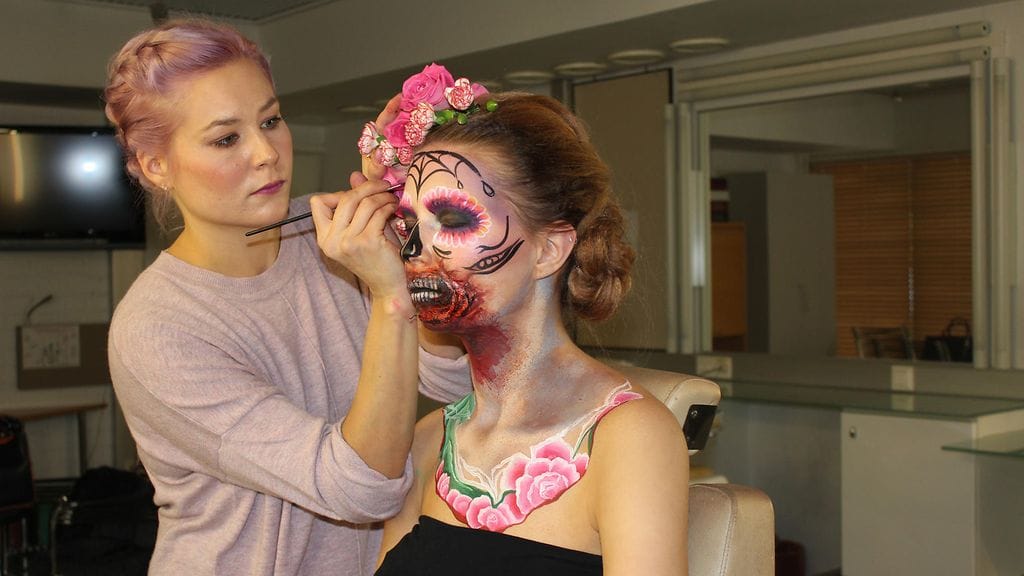 Emma Räsänen loihtii mallilleen Sugar Skull -meikkiä.