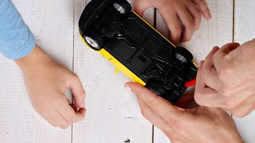 Isä ja poika korjaavat leluautoa