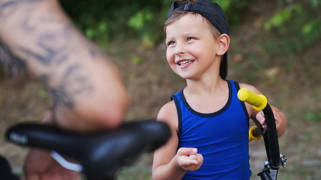 Isä ja poika opettelevat pyöräilemään. Kuvituskuva.