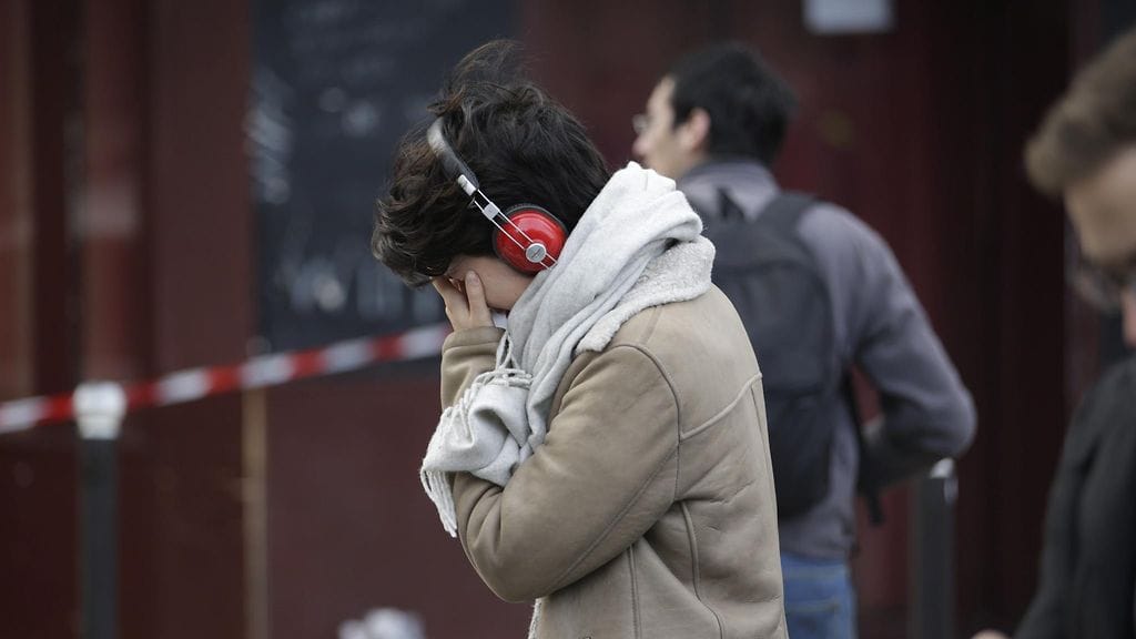 Nainen suree iskun kohteena olleen ravintolan edustalla Pariisissa.