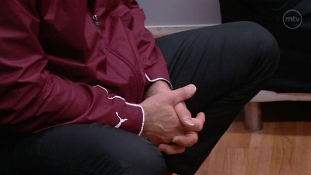 Mies istuu säilöönottokeskuksessa.